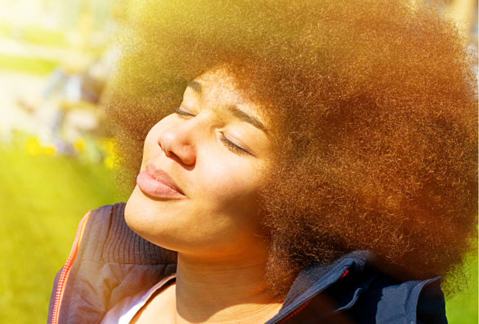 Black woman with natural 4C hair smiling, representing the regenerative power of 4C hair follicles and holistic scalp health